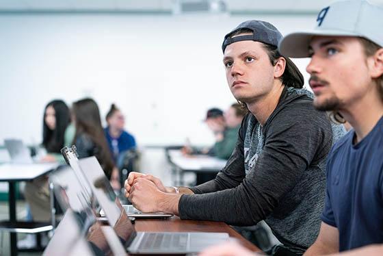 Photo of an older female faculty member leaning over a Chatham University student and pointing to a computer