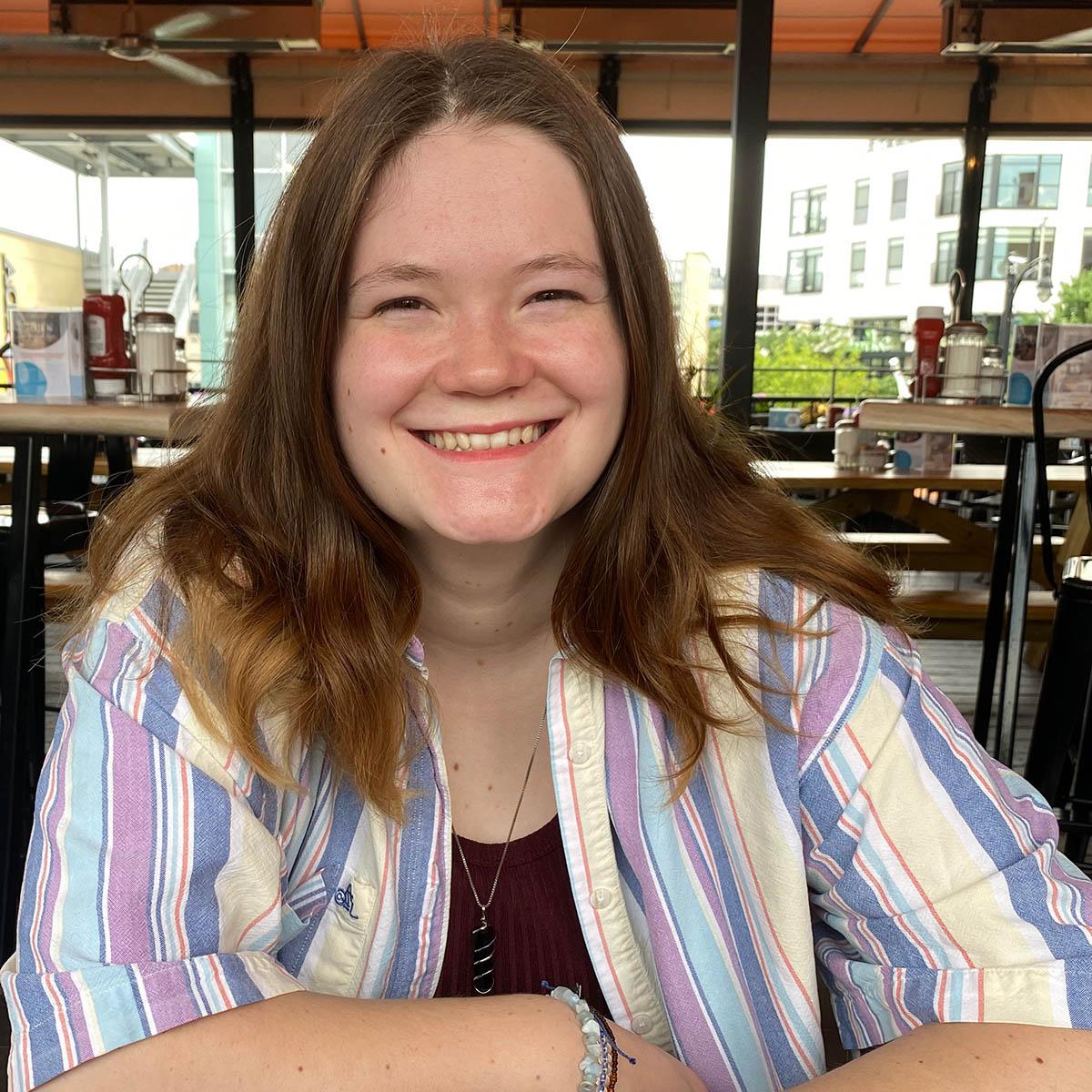 Photo of a smiling young woman in a striped collared shirt