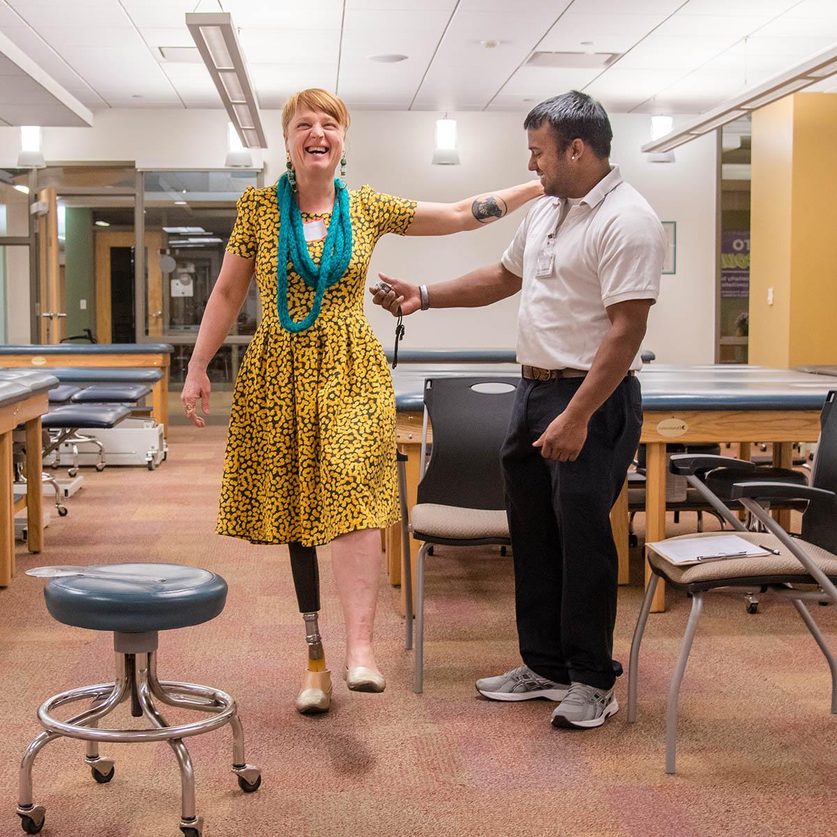 Photo of a Chatham physical therapy student assisting a woman amputee as she tries on a new prosthetic leg